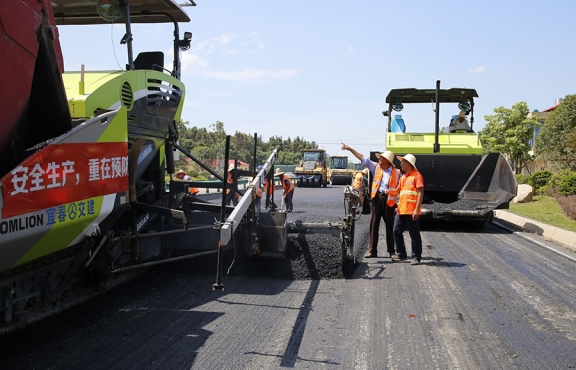 攤鋪機(jī)、壓路機(jī)等設(shè)備緊張有序運(yùn)行，高達(dá)170℃的瀝青混合料炙烤著公路人